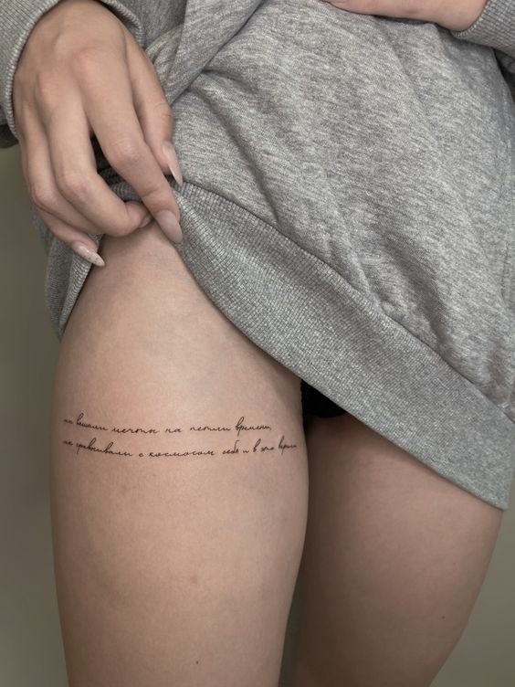 Tattoo with an inscription on the hip for women