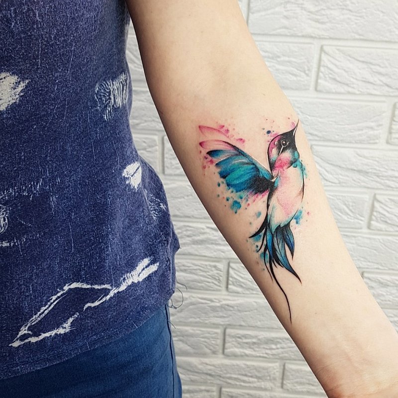 Colored hummingbird tattoo on the forearm for women