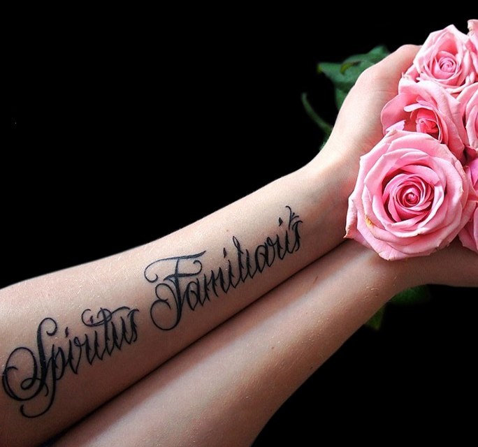 Large tattoo with an inscription on the forearm for women