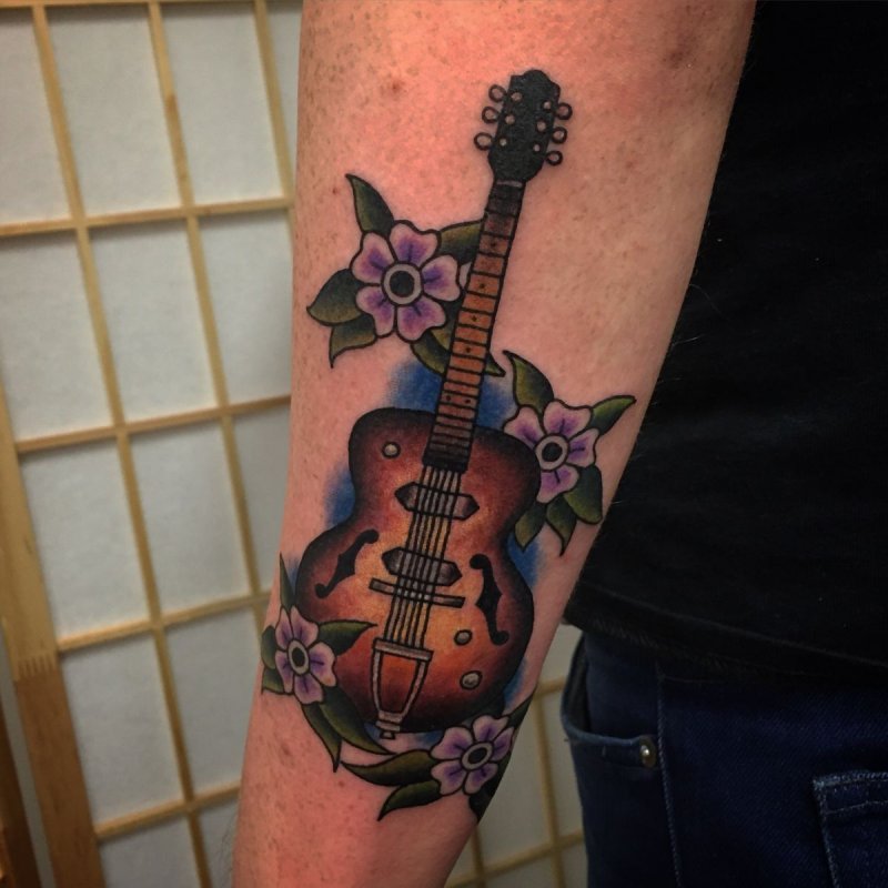 Guitar tattoo with flowers on forearm for men