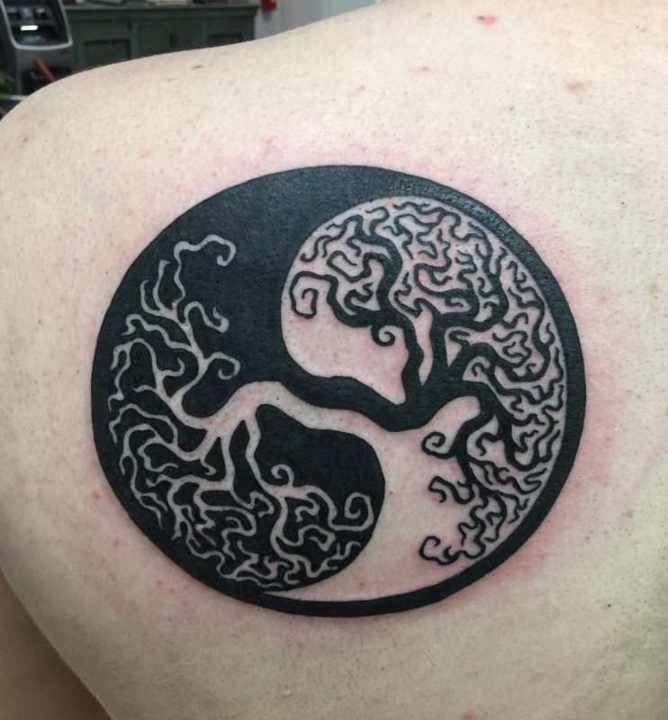 Yin-yang tattoo on the shoulder blade for men