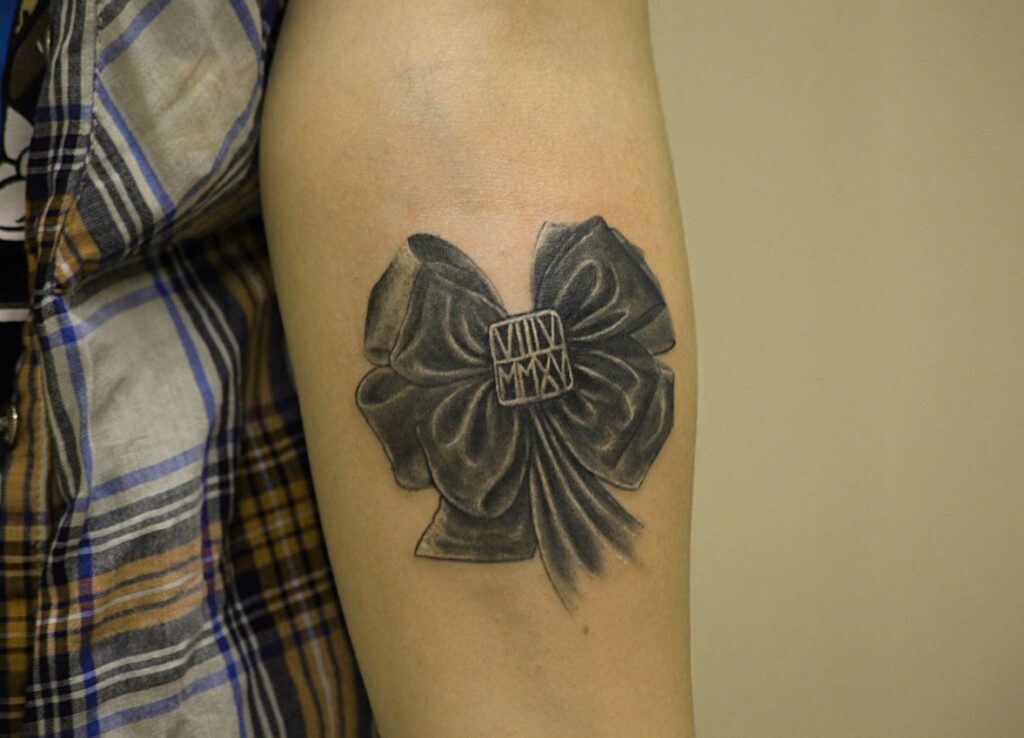 Bow tattoo on forearm for women