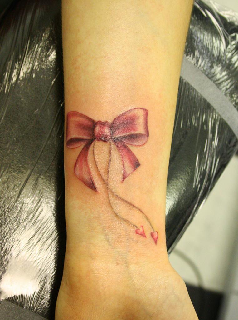 Bow tattoo on arm for women