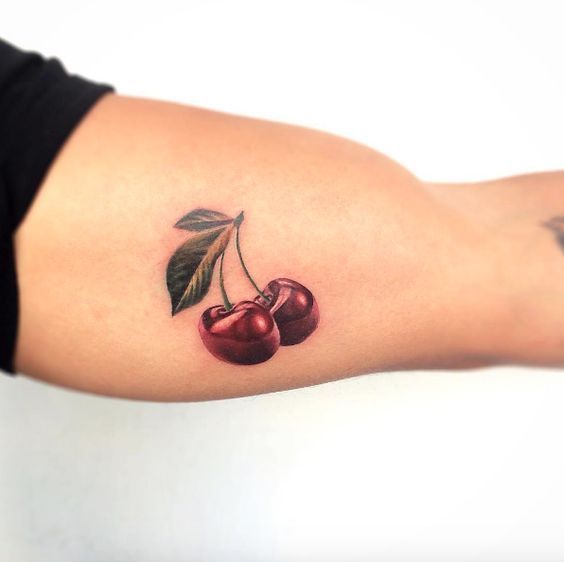 Cherry colored tattoo on biceps for men