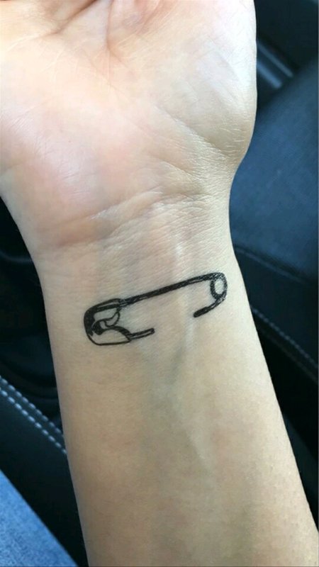 Large pin tattoo on wrist for women