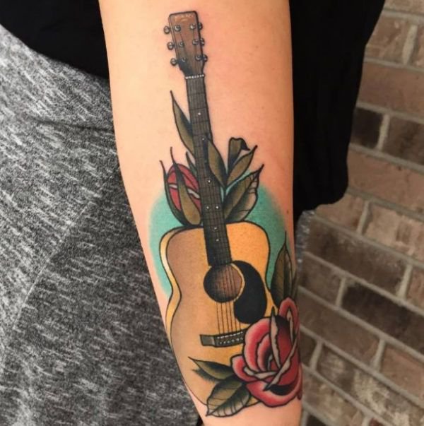 Guitar tattoo with flowers on the arm for women