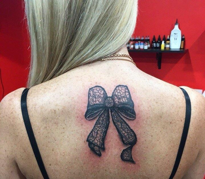 Bow tattoo on back for women